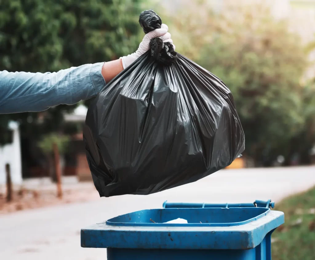 Close up of someone throwing away trash in residential garbage can.